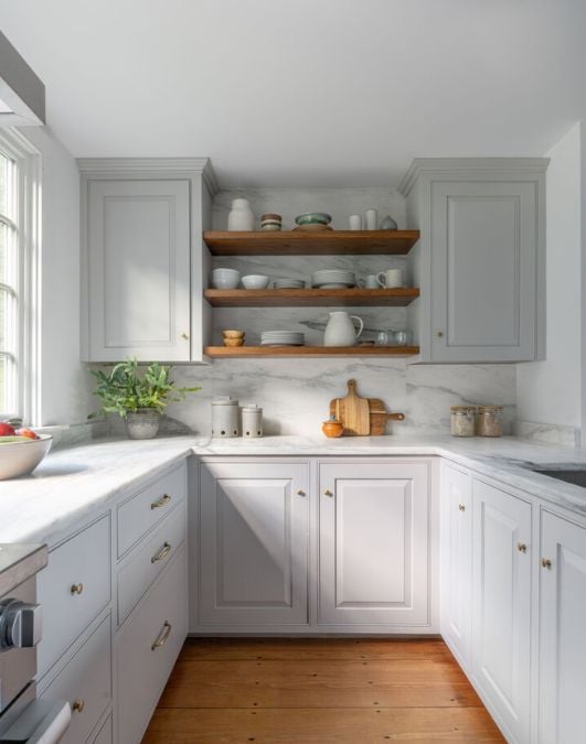 A kitchen with white cabinets and wooden floors