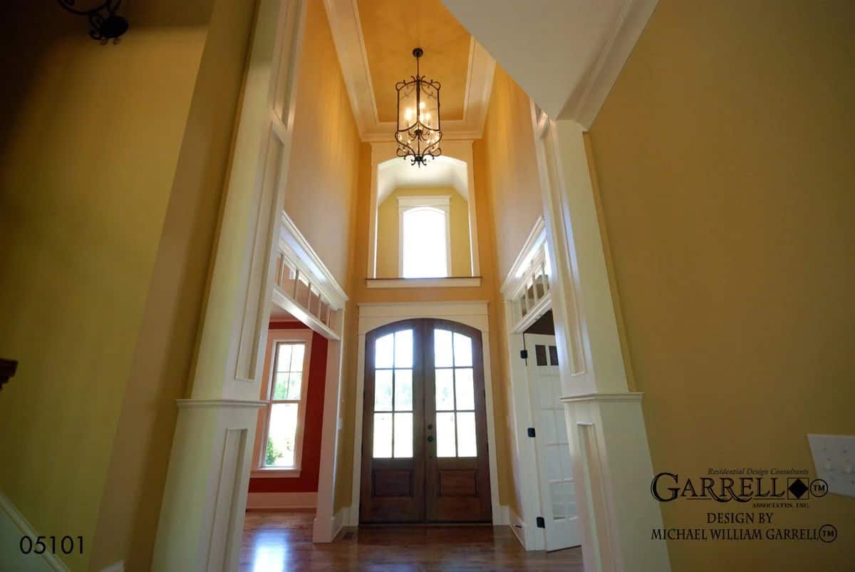 Foyer with a two-story ceiling and a French front door topped with a transom.