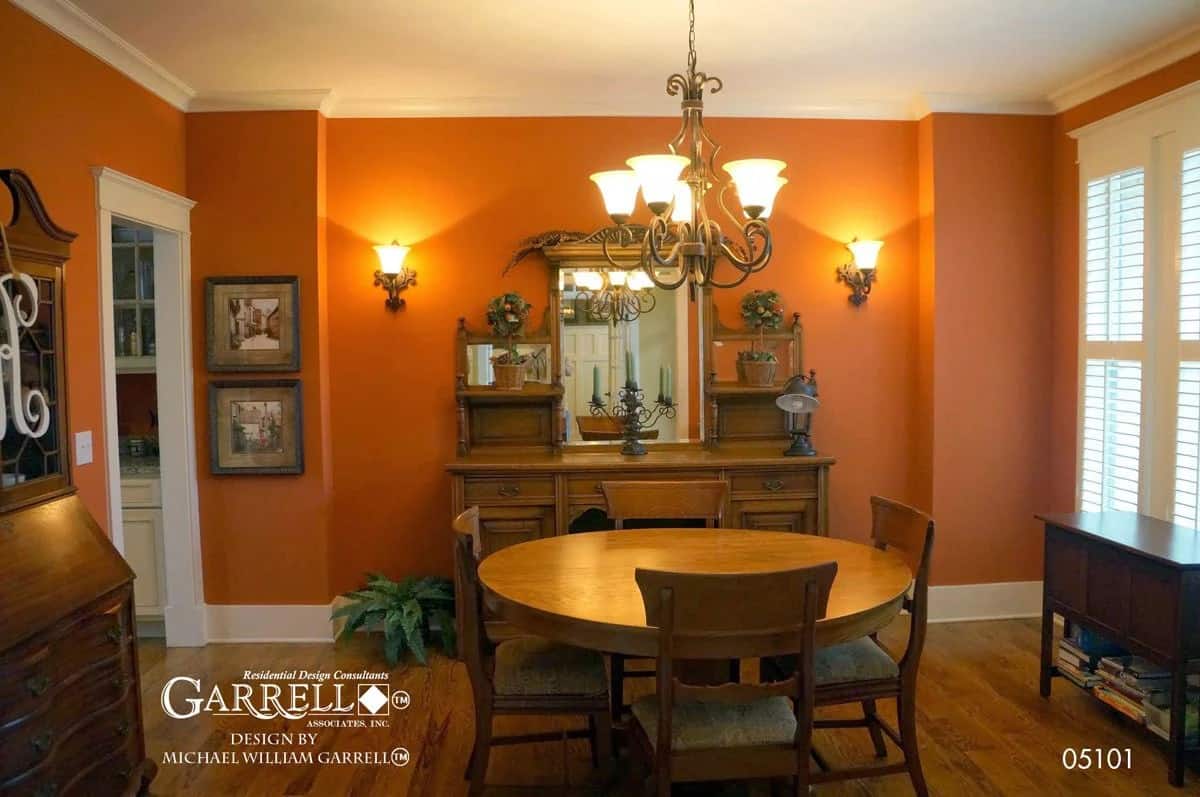 Dining room with a round dining set and wooden cabinets against the red walls.