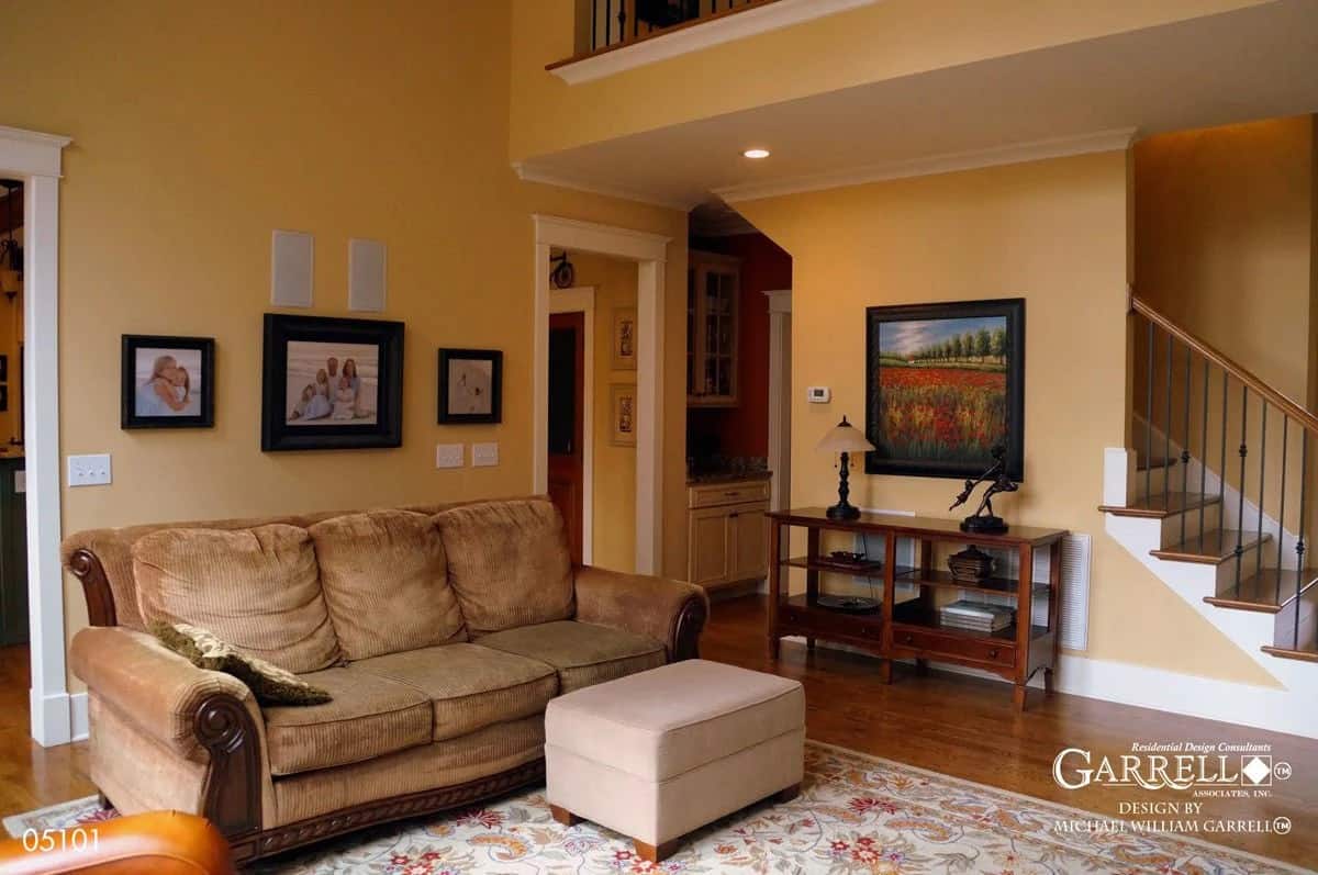 Grand room with yellow walls, a velvet sofa, and an ottoman over a floral area rug.