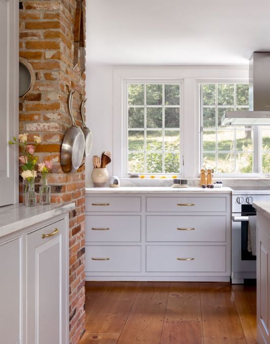 A kitchen with a brick wall and white cabinets