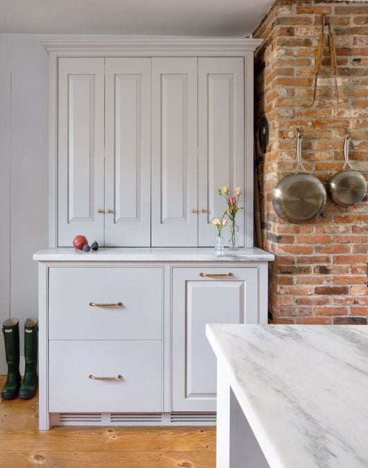 A kitchen with a brick wall and white cabinets