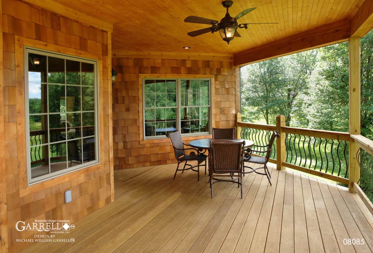 Rear covered deck with wood-paneled ceiling and a round dining set over the wide plank flooring.