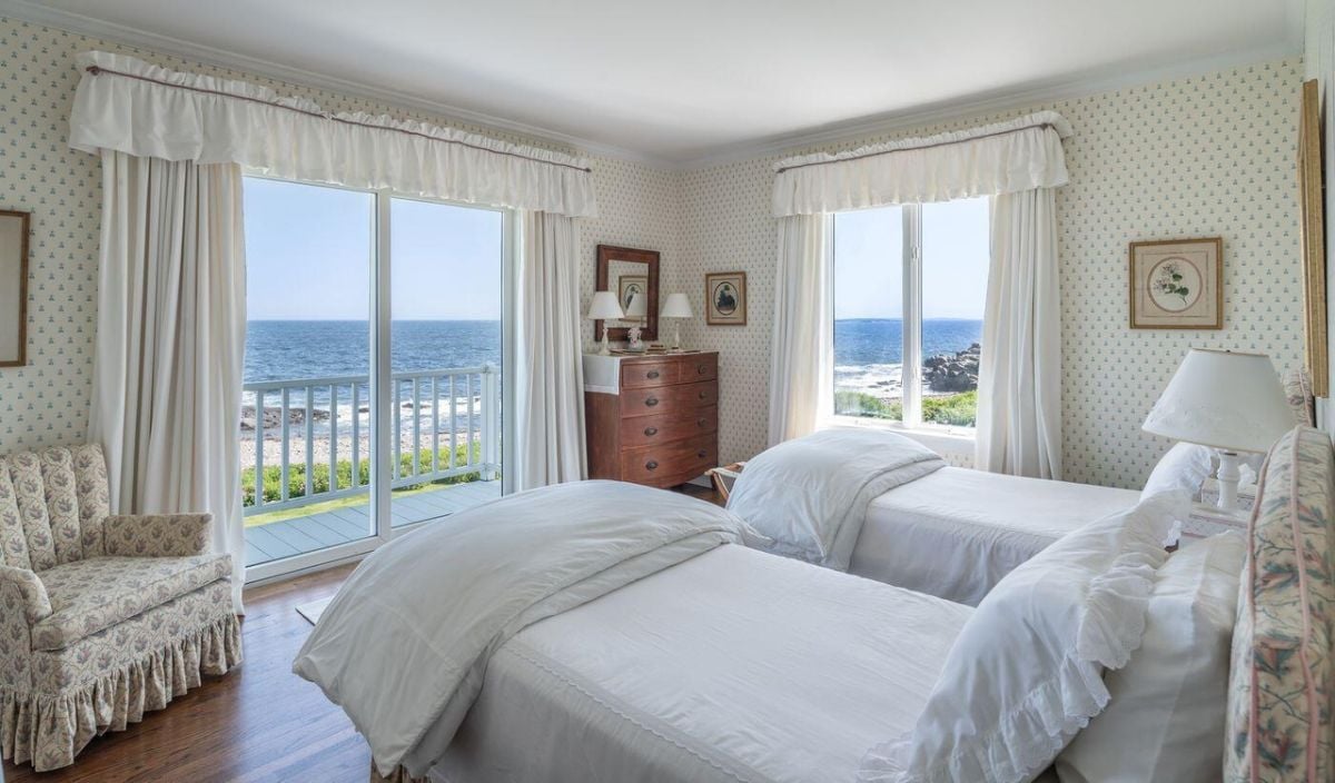 Bedroom with wood flooring, two beds, sliding glass door, and glass windows.