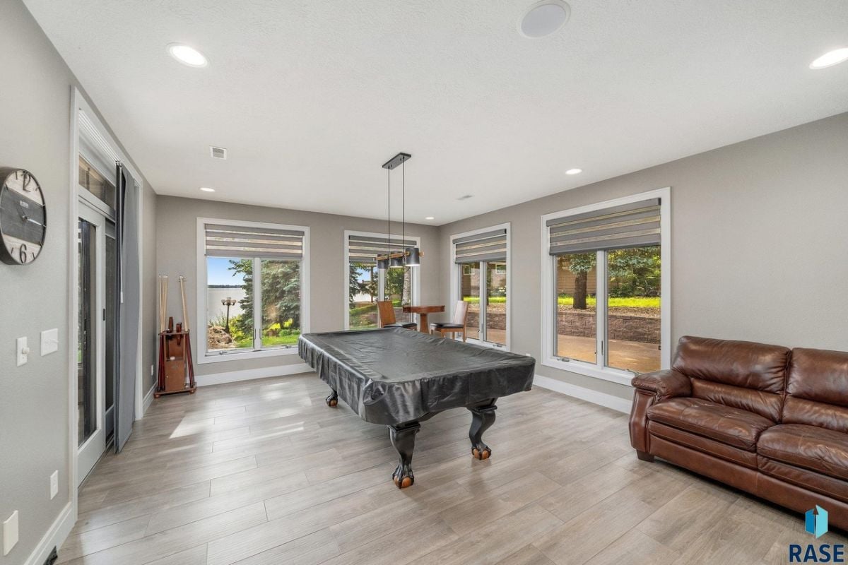 Billiards room with couches, wood flooring and custom lighting.