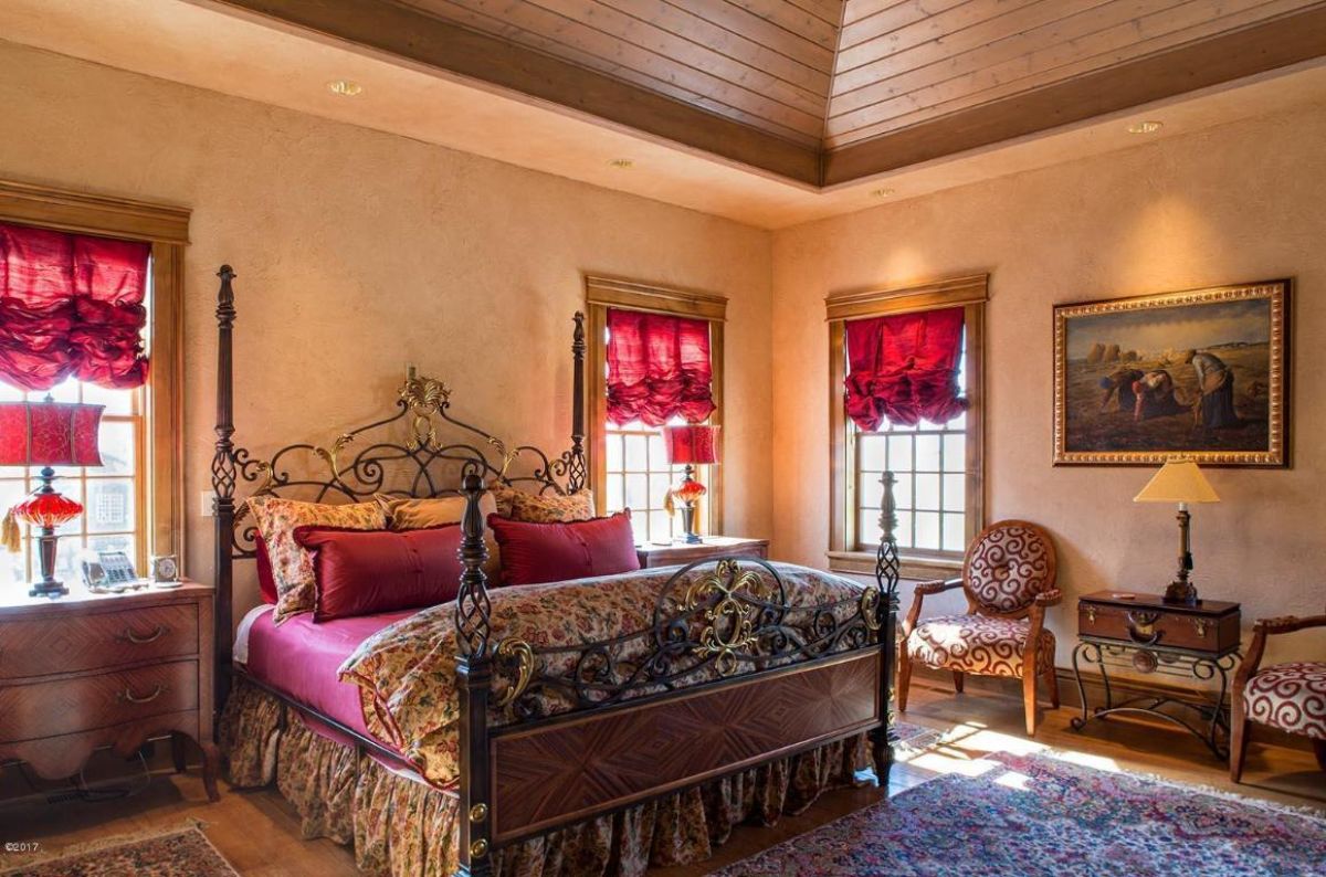 Bedroom with a large bed custom lighting, and wood flooring.
