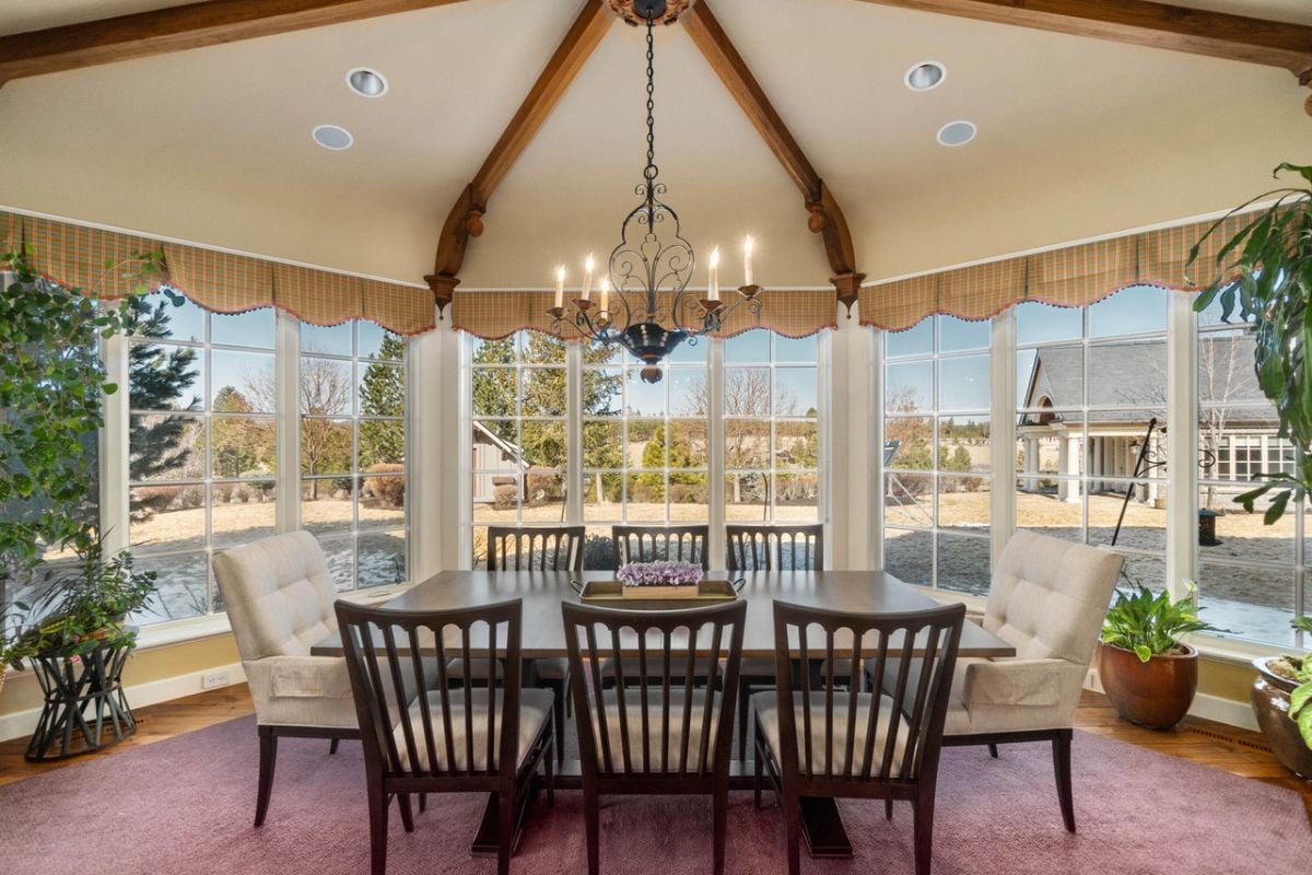 Breakfast area with a chandelier, glass windows, and a wooden table.