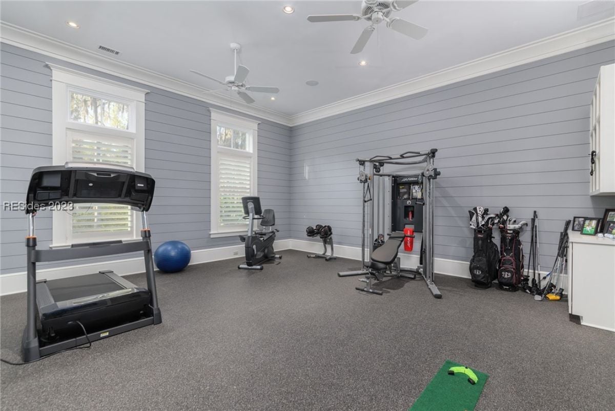 Home gym with carpet flooring, custom lighting and ceiling fans.