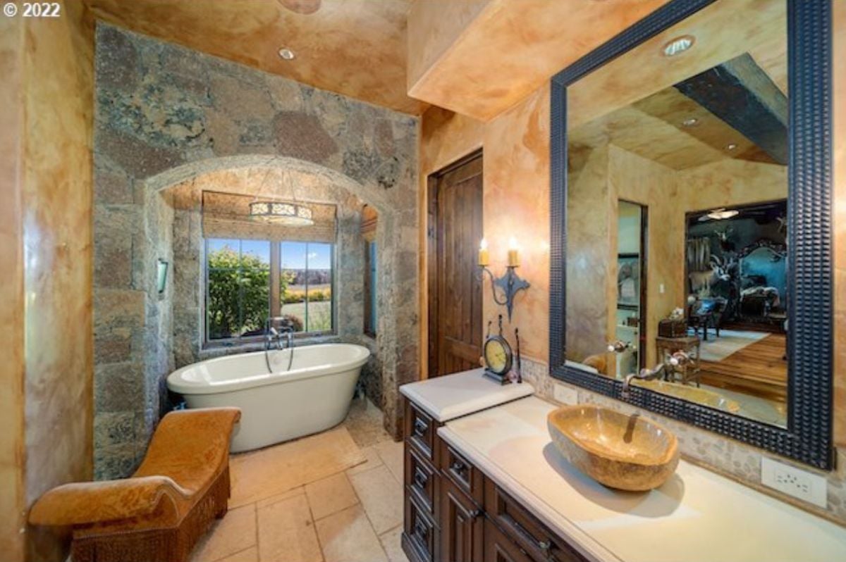 Bathroom with a sink, a bath tub and a large mirror.