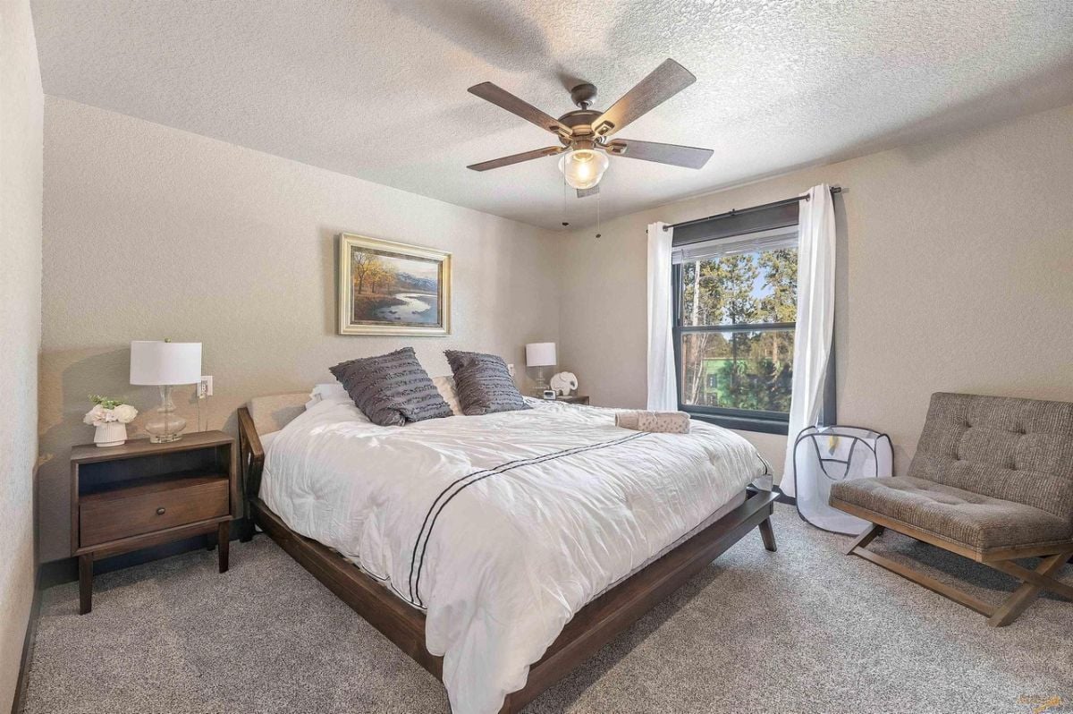 Bedroom with carpet flooring, a ceiling fan and a large bed.