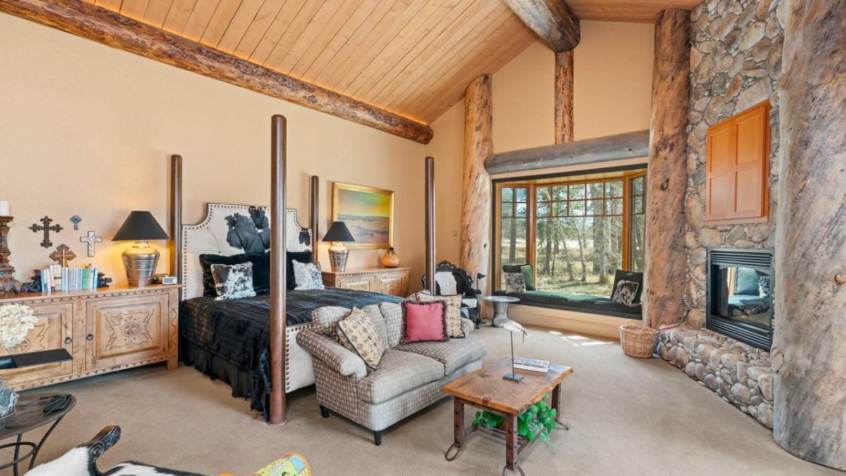Bedroom with a large bed, a fireplace and glass windows.