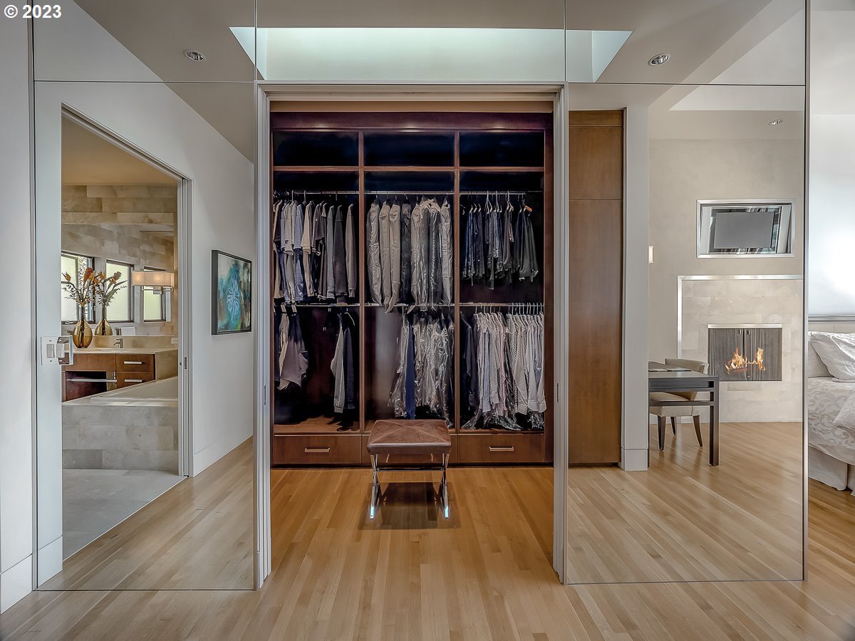Walk-in closet with glass doors and wood flooring.