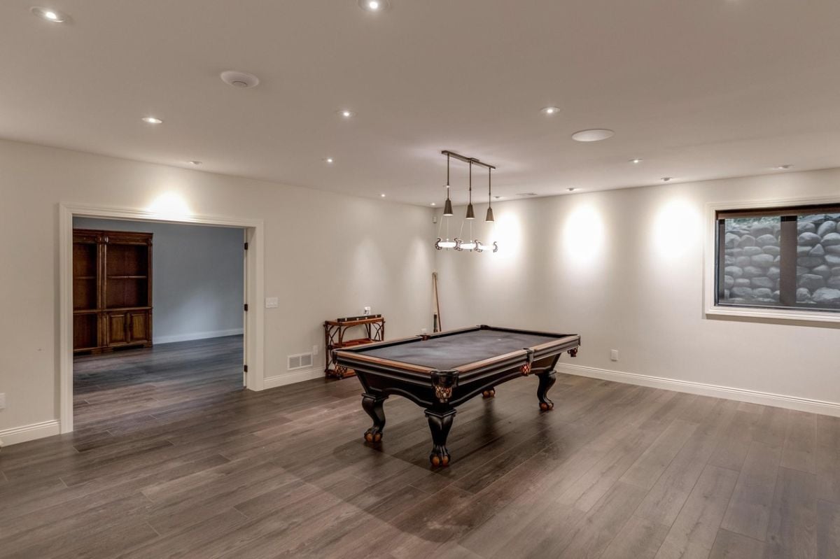 Billiards room with wood flooring and custom lighting.