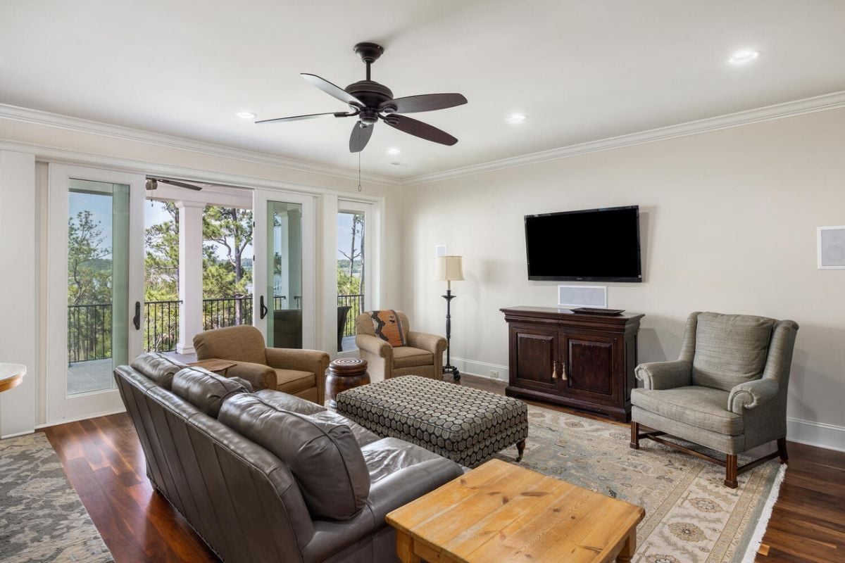 Media room with couches, large flat screen TV and a ceiling fan.