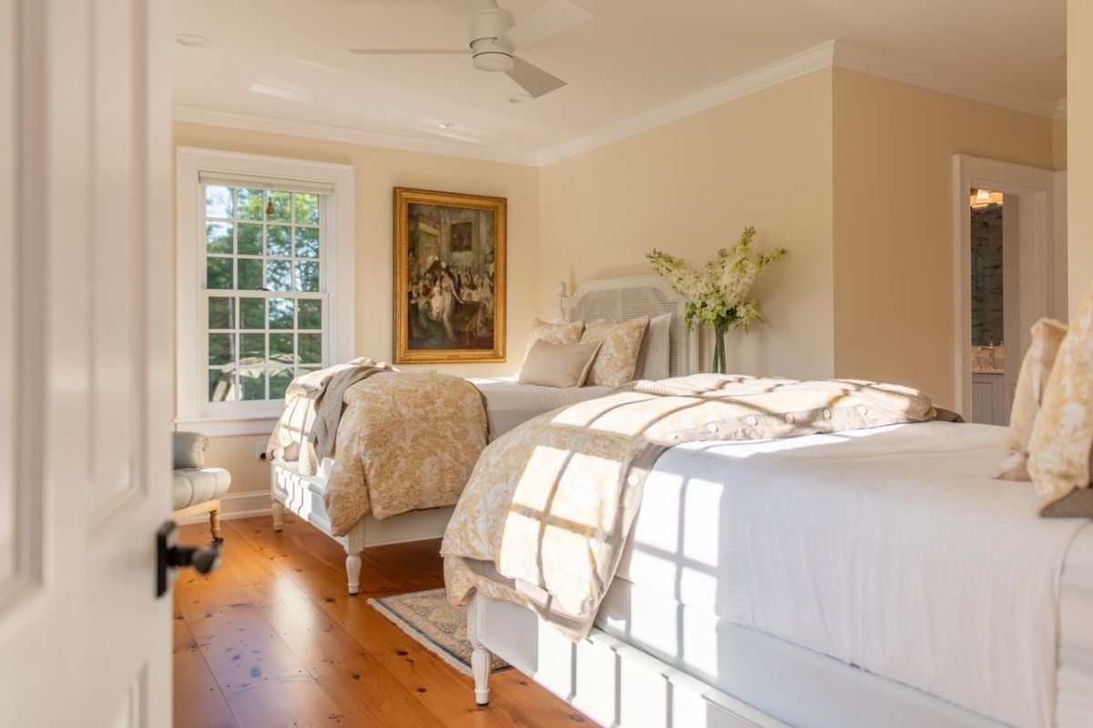 Bedroom with wood flooring, two beds and glass windows.
