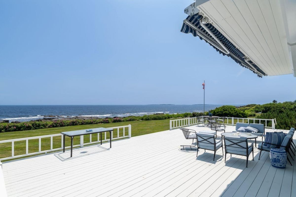 Patio with tables, chairs, and a view of the ocean.
