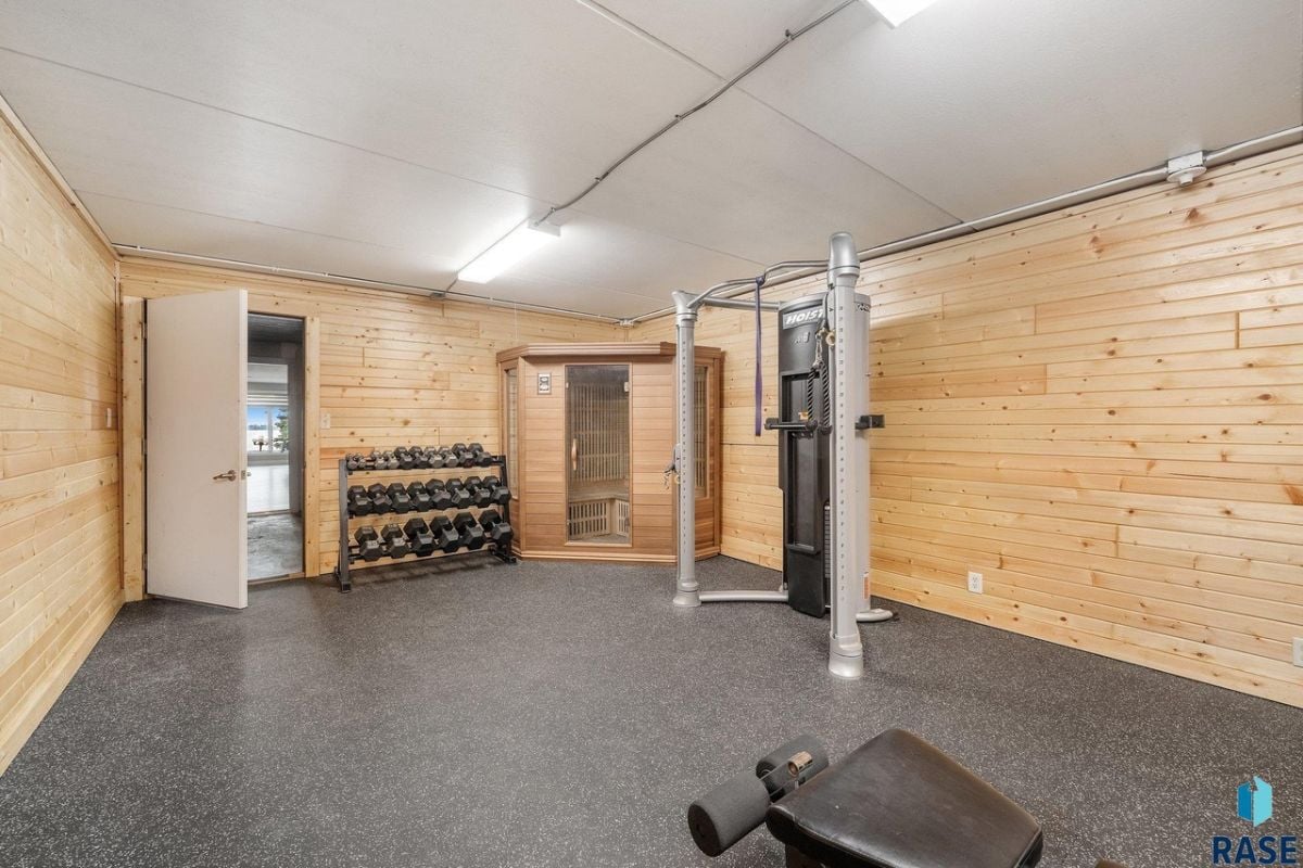 Home gym with workout equipment and wooden walls.