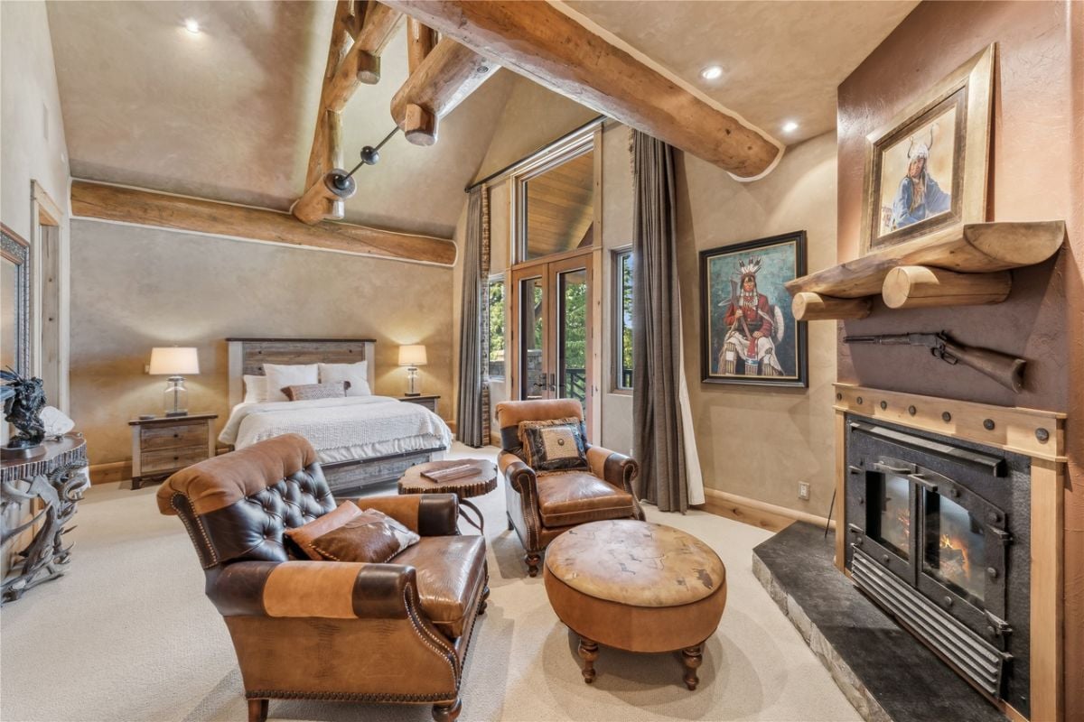 Bedroom with carpet flooring, a fireplace and a large bed.