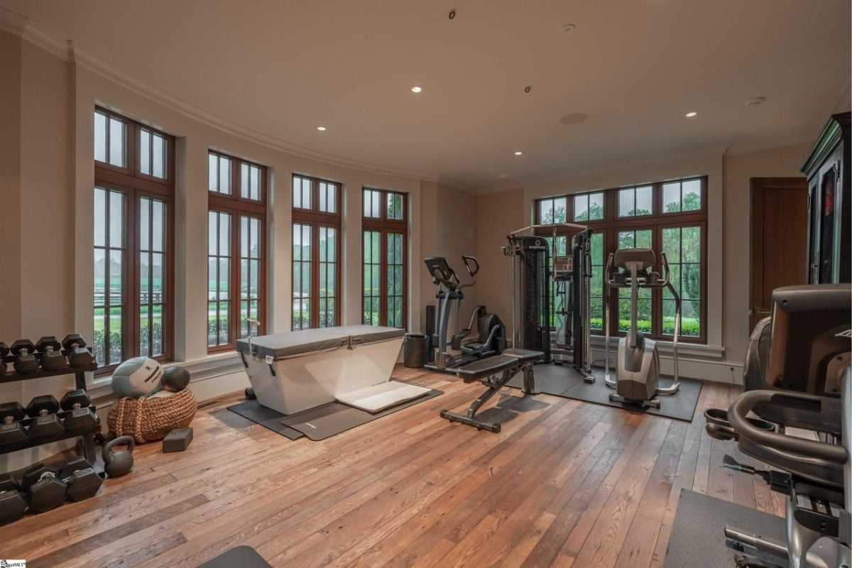 Home gym with workout equipment, wood flooring, and large glass windows.