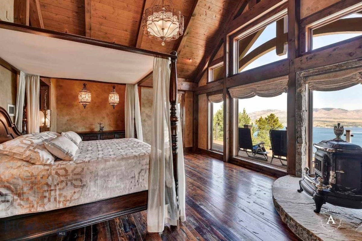 Bedroom with open beam ceiling, a large bed and a fireplace.
