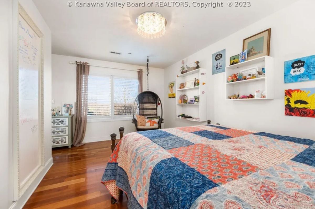 Bedroom with wood flooring, glass windows and a large bed.