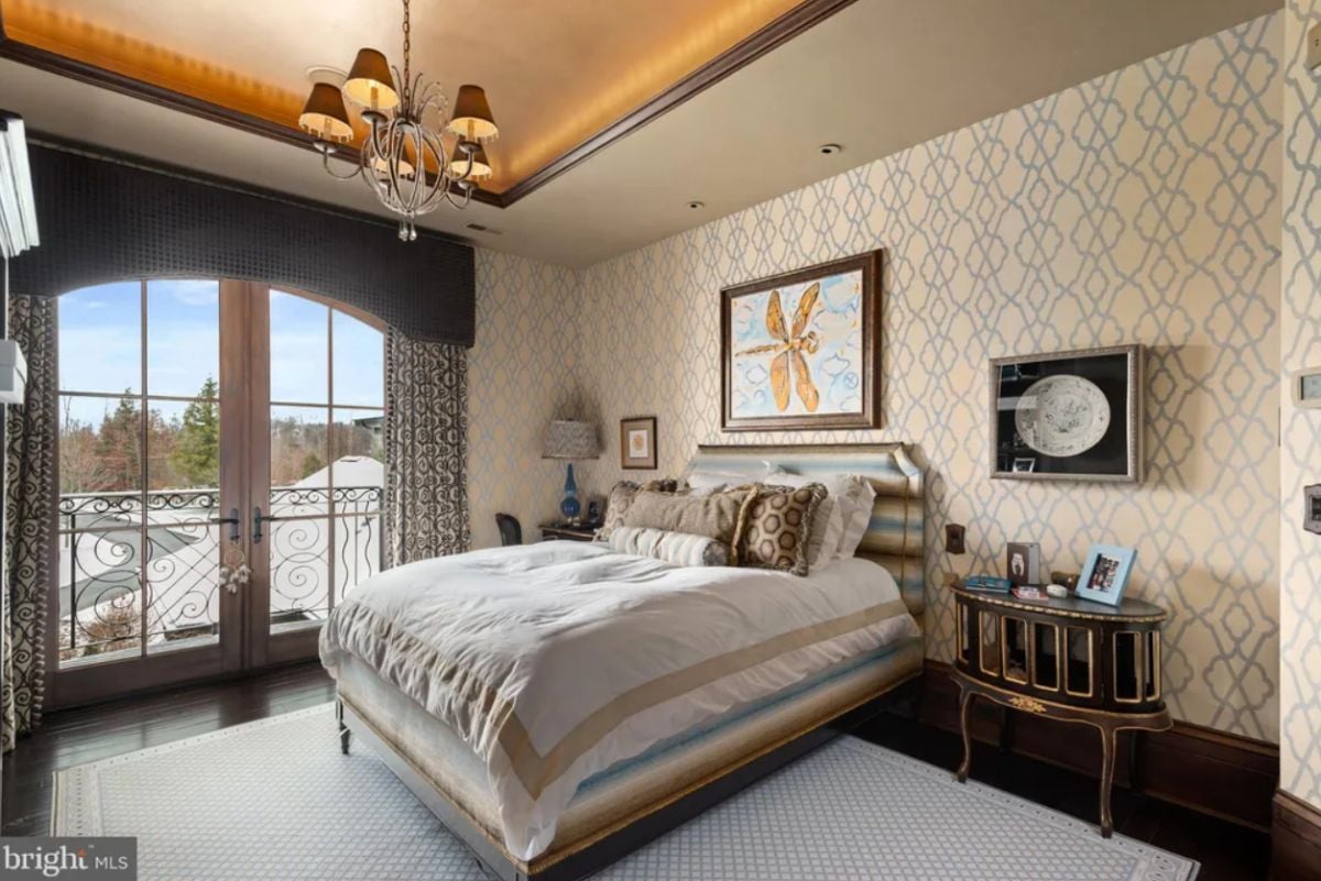 Bedroom with wood flooring, a large rug and glass doors.