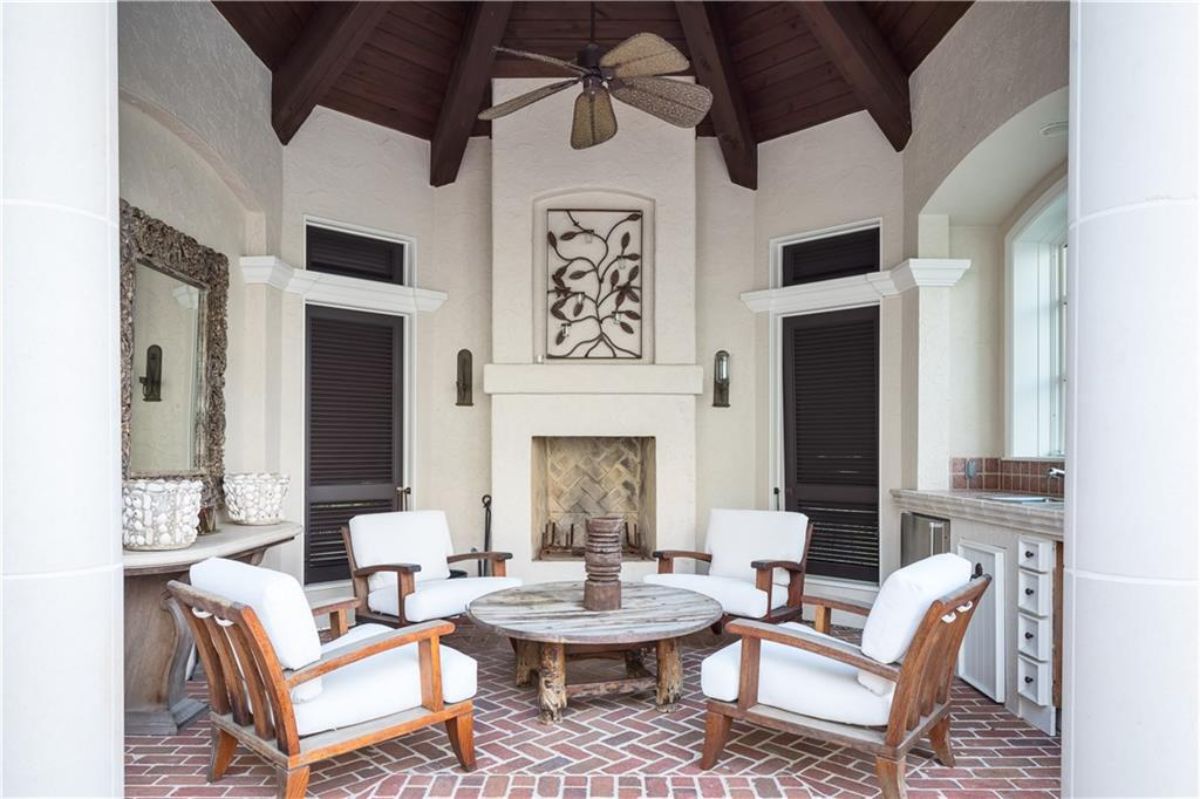 Outdoor living space with white chairs and a center table.