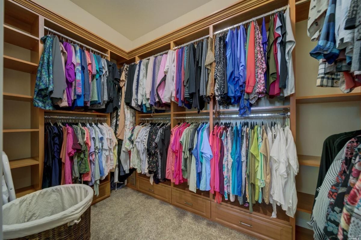 Walk-in closet with shelves, hangers and clothes.