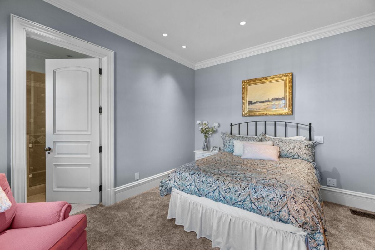 Bedroom with carpet flooring, a couch, and a large bed.
