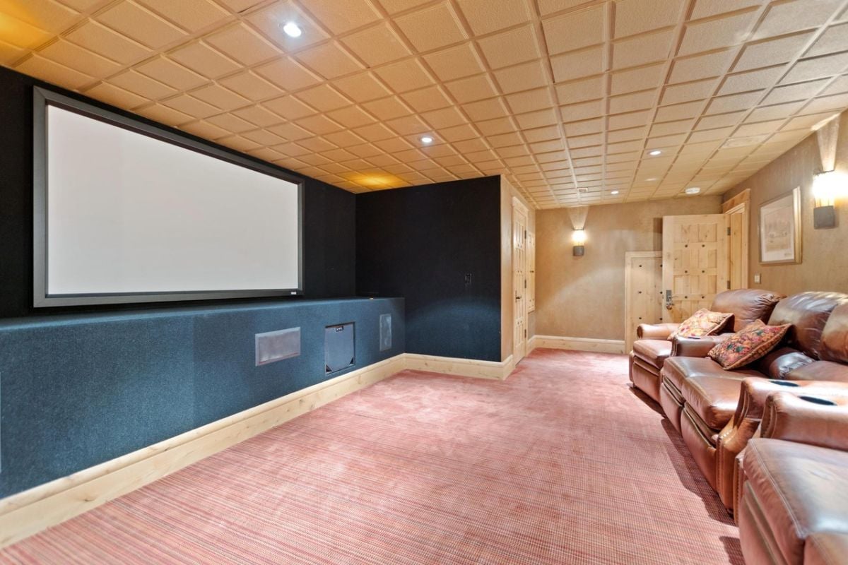 Movie room with leather couches and huge projector screen.