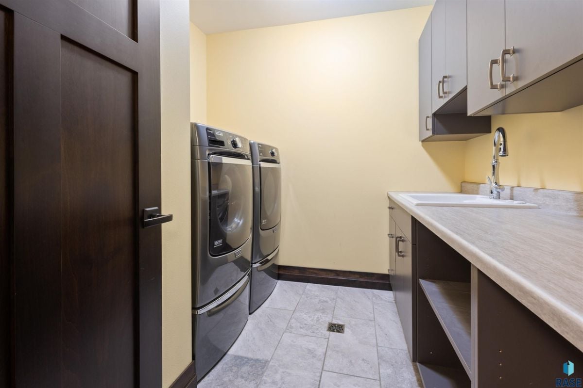 Laundry room with a sink, cabinets, and tile flooring.