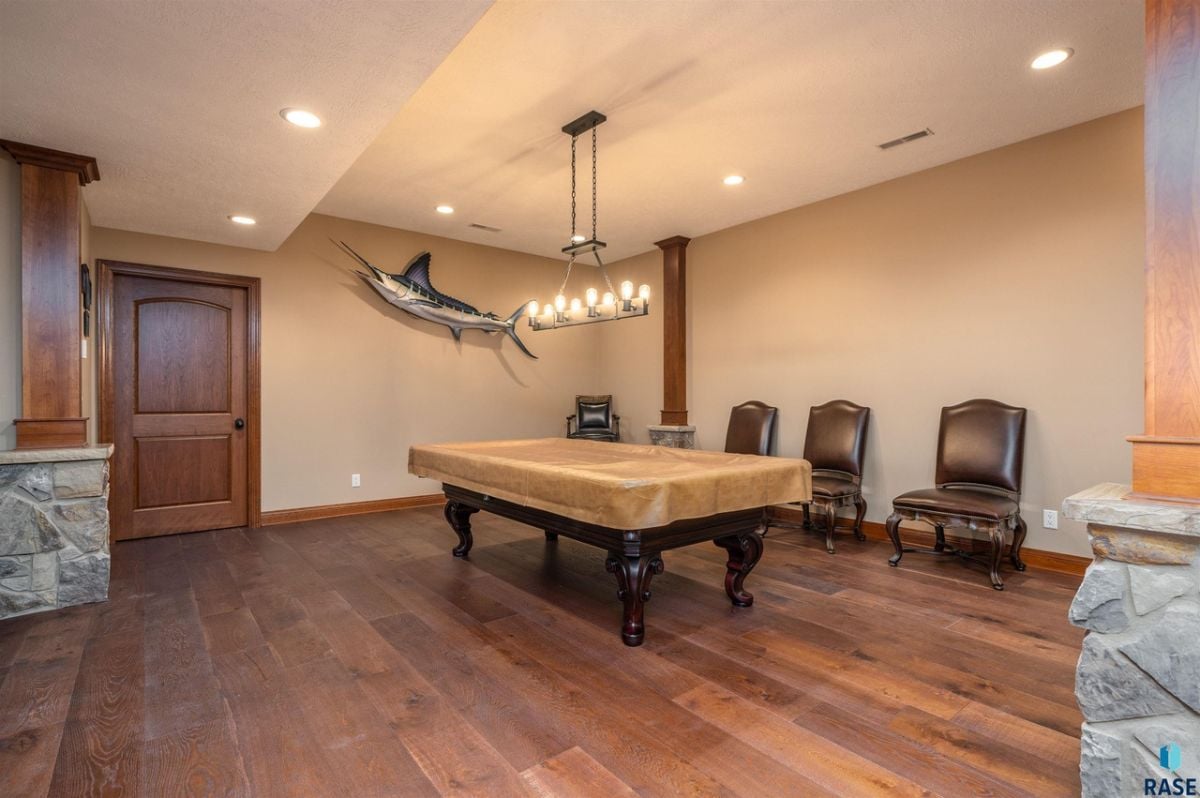 Billiards with wood flooring and custom lighting.