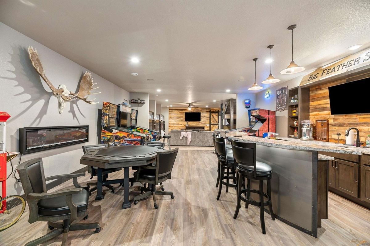 Recreation room with wood flooring, custom lighting and a bar.
