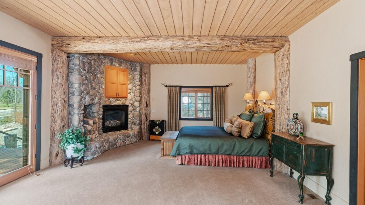 Bedroom with carpet flooring, a large glass door, and a fireplace.