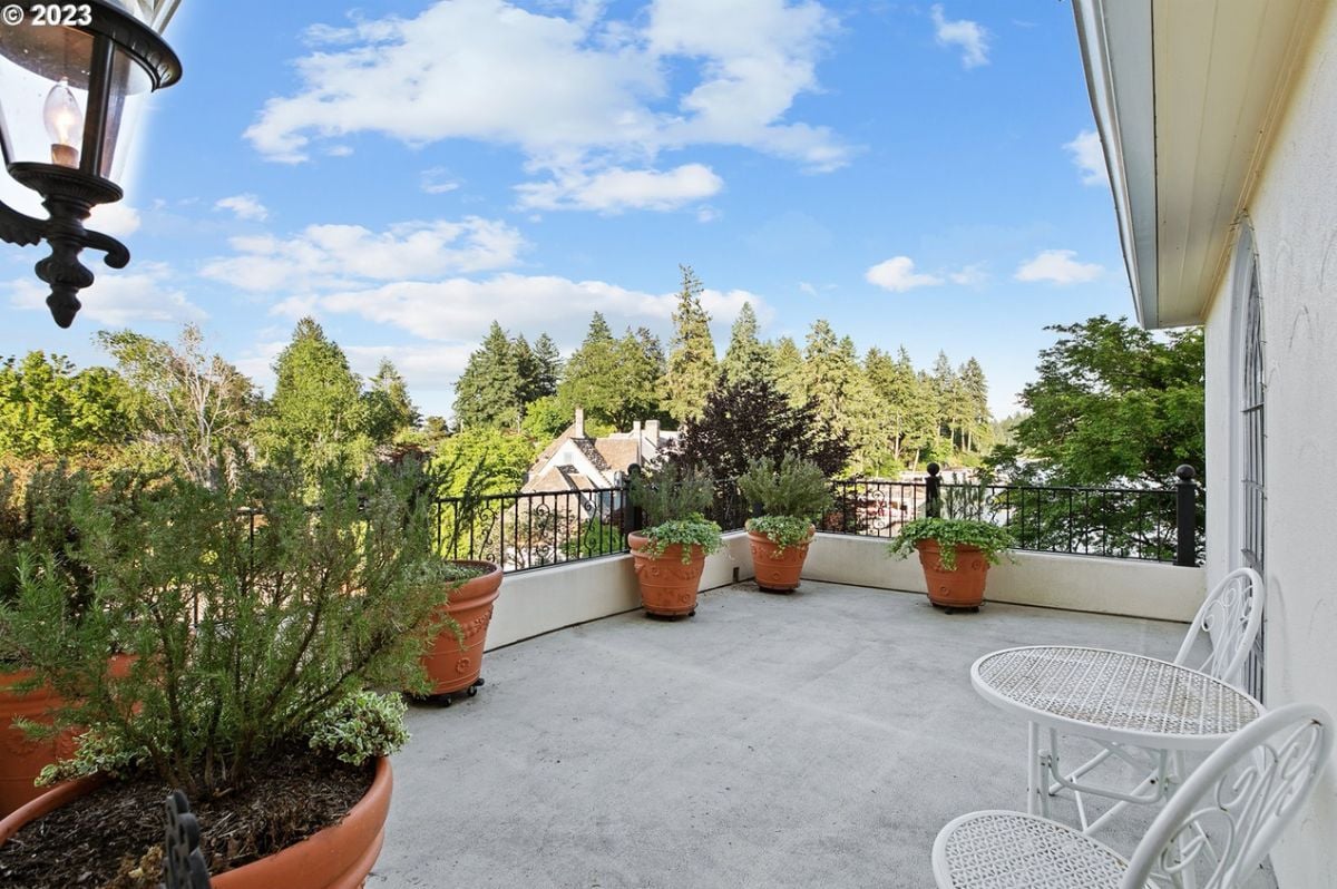 Balcony with potted plants, table and chairs.