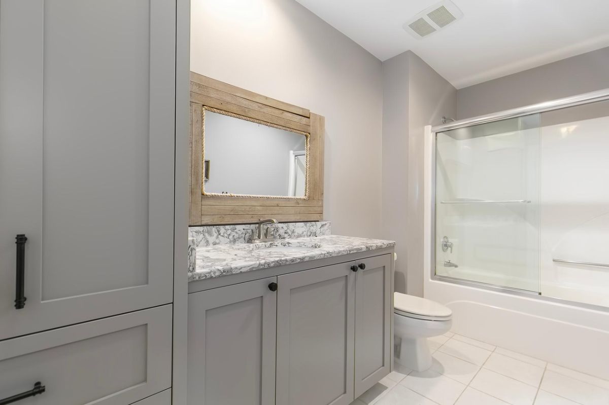 Bathroom with a sink, custom cabinetry, shower, and toilet.