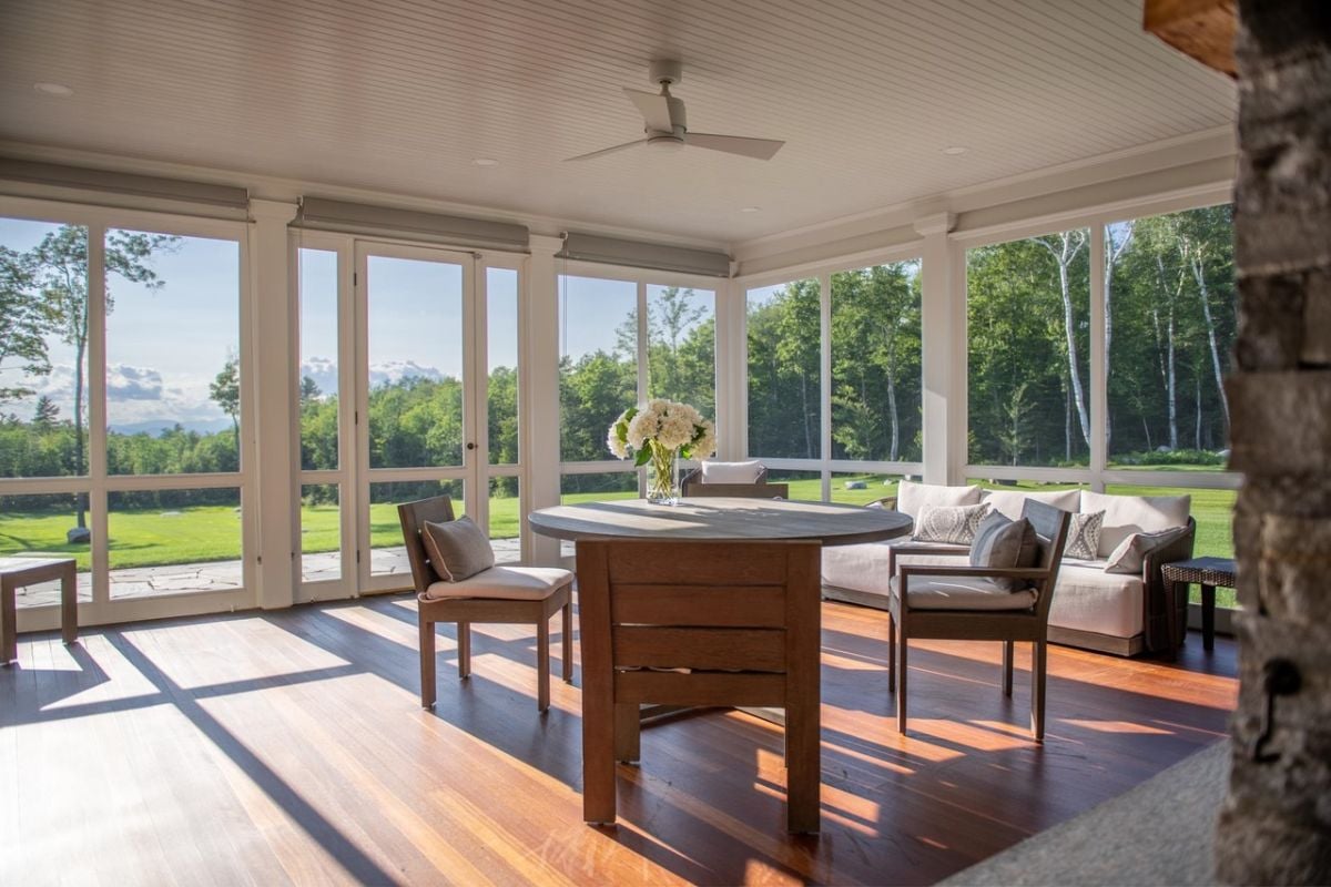 Screened porch with a table, chairs, and a view of the trees.