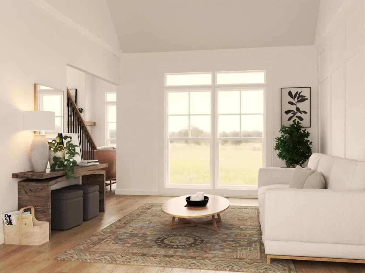 Living room with a vaulted ceiling, a gray sofa, and a wooden console table with ottomans underneath.