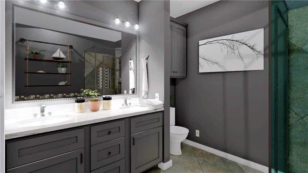 Primary bathroom with a dual sink vanity and a toilet area with overhead cabinet.