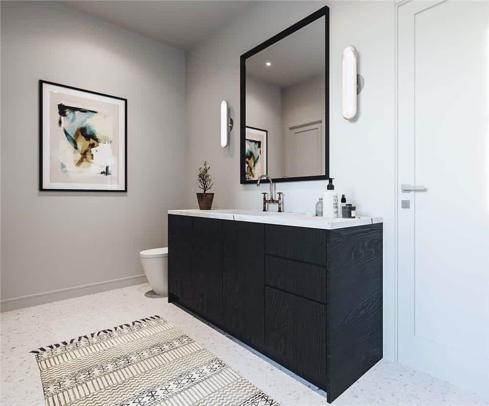 Primary bathroom with a toilet and a dual sink vanity topped with a framed mirror.