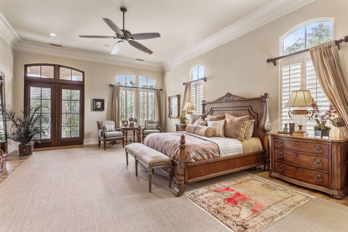 Bedroom with a large bed, glass doors, glass windows, and a ceiling fan.