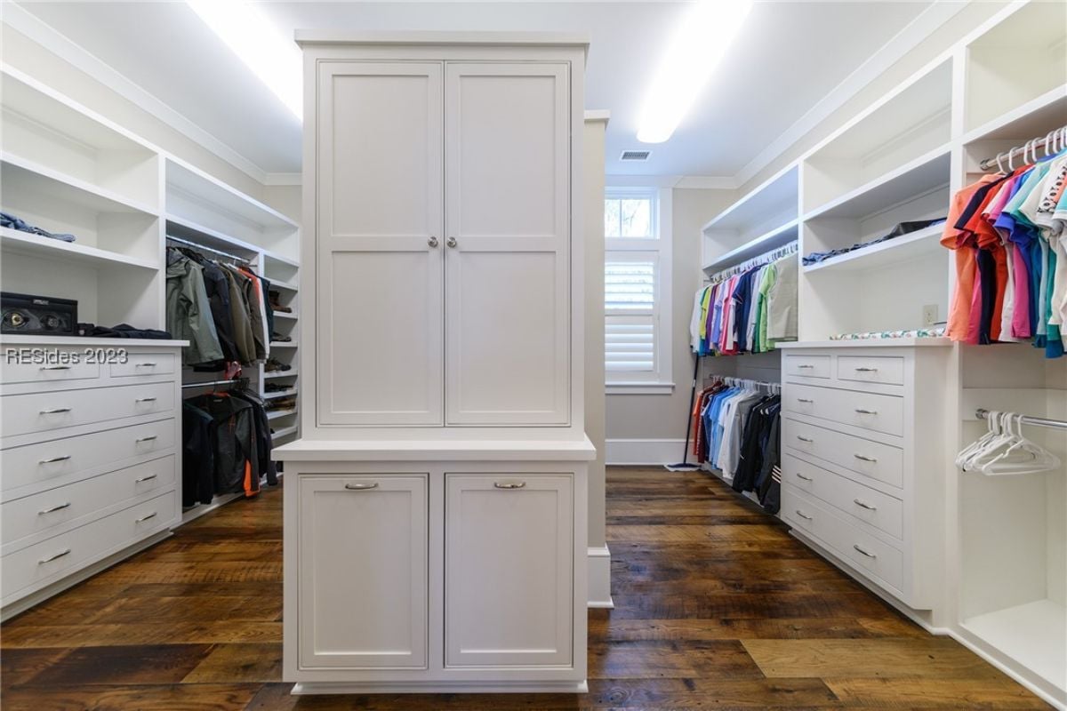 Walk-in closet with white cabinets and drawers.