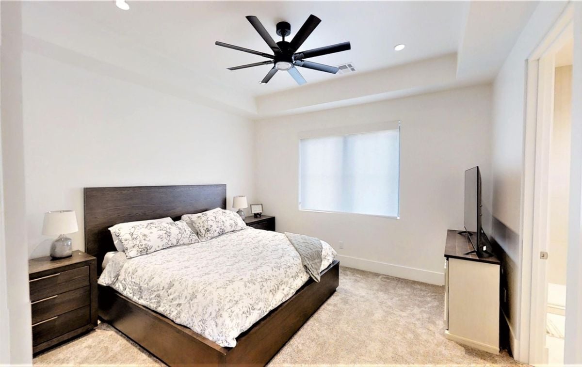 Bedroom with carpet flooring, custom lighting, a TV and a ceiling fan.