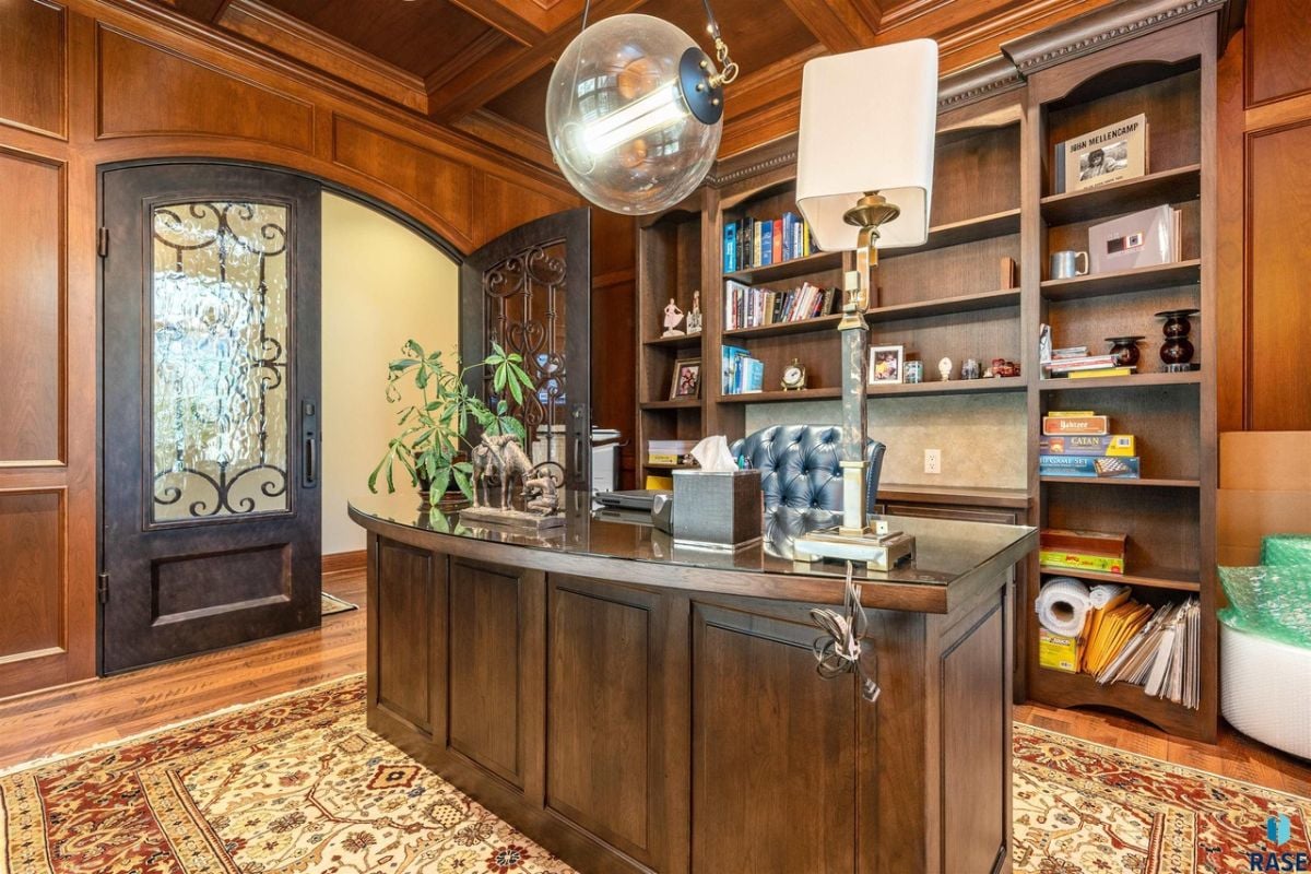 Home office with wood paneling and a large desk.