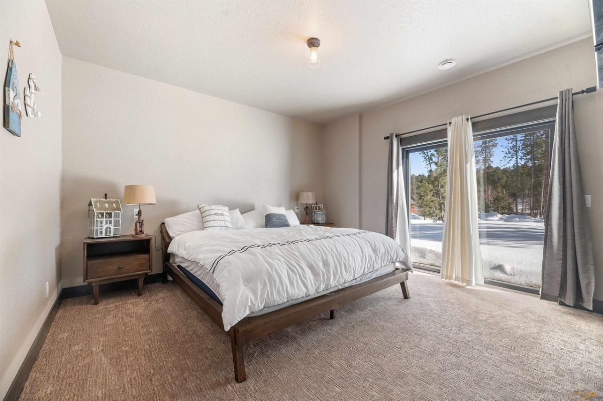 Bedroom with carpet flooring, a large bed, and sliding glass doors.