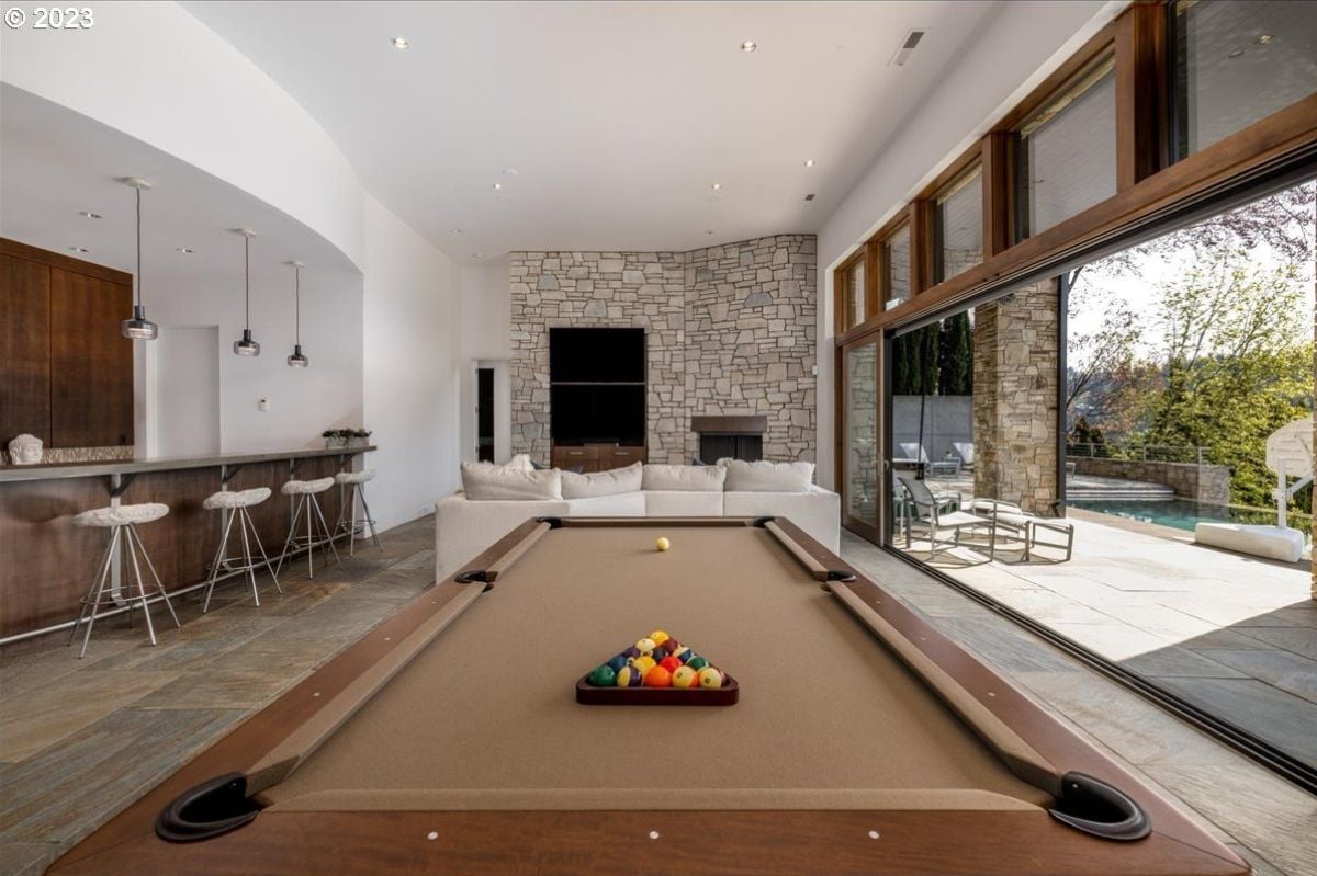 Recreation room with billiard table, couches, TV, and a bar.