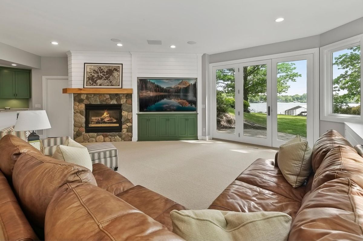 Media room with leather couches, a large TV, and a fireplace.