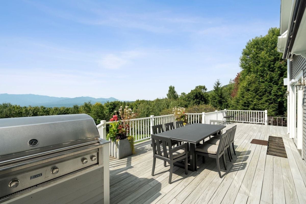 Balcony with table, chairs, grill, and a view of the mountains.