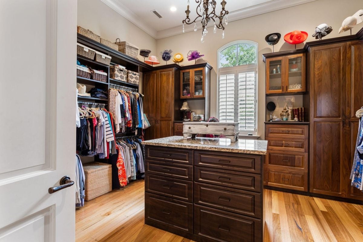 Walk-in closet with a chandelier and custom cabinetry.