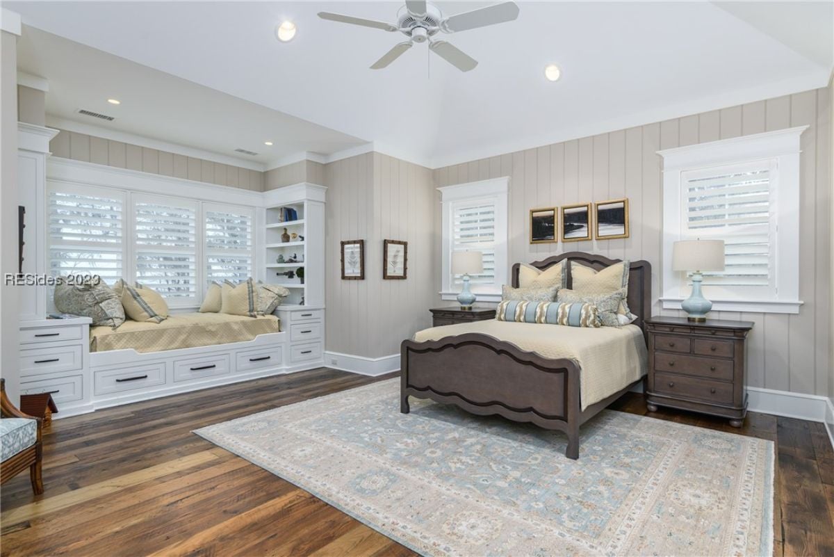 Bedroom with wood flooring, custom lighting and a large bed.